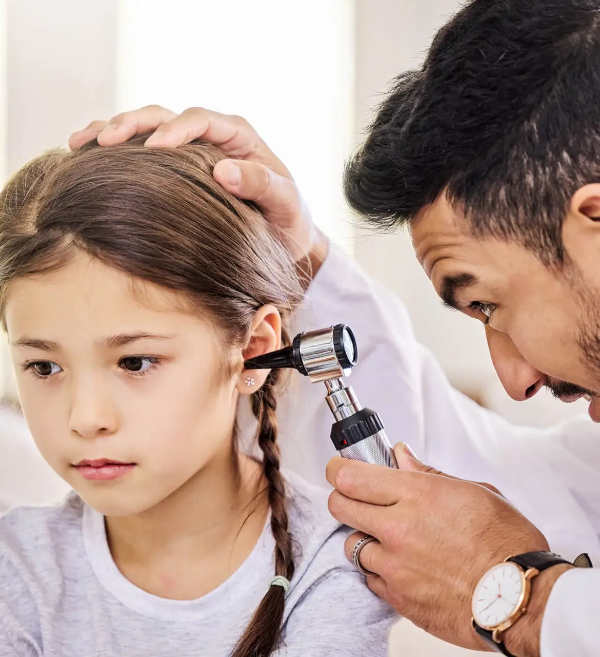 A doctor examining a child's ear with an otoscope