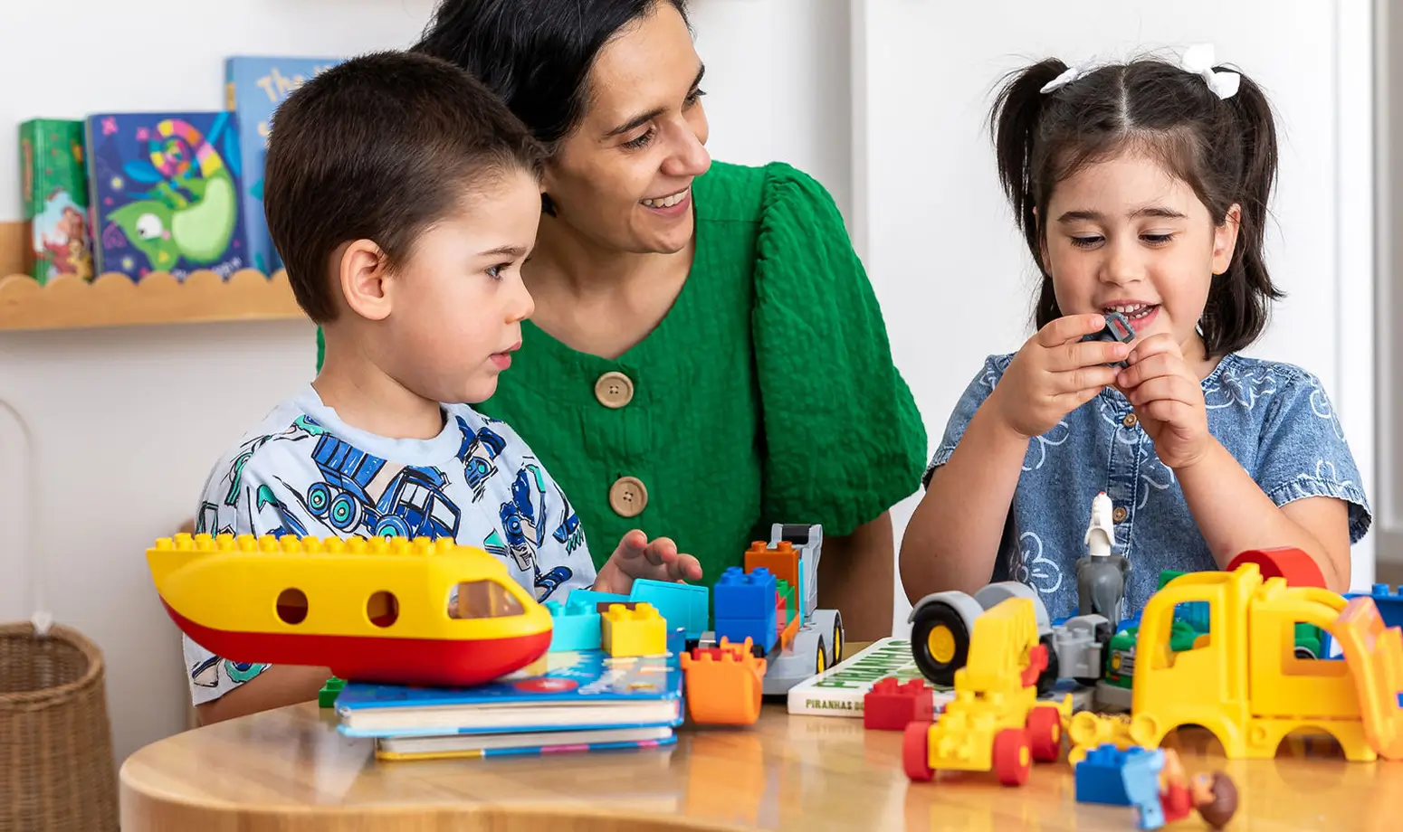 Parent and two children sitting at table playing with toys